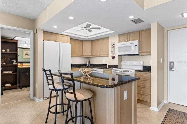 kitchen with white appliances, a raised ceiling, ceiling fan, light tile patterned floors, and a center island