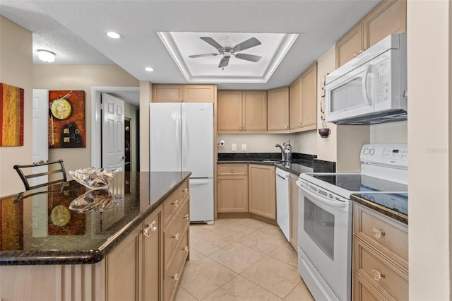 kitchen with a tray ceiling, light brown cabinets, light tile patterned flooring, and white appliances