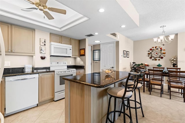 kitchen featuring ceiling fan with notable chandelier, white appliances, a kitchen island, hanging light fixtures, and light tile patterned flooring