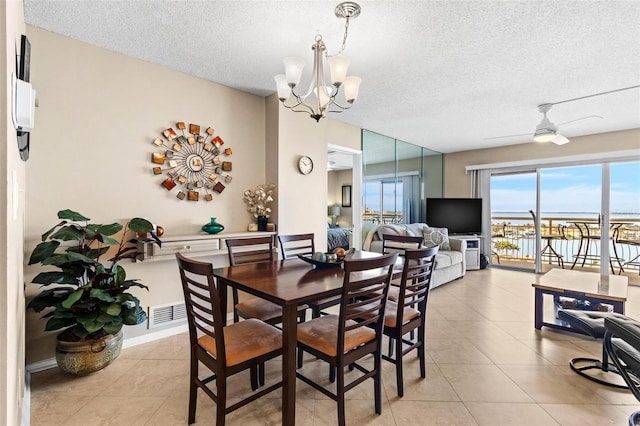 dining space with ceiling fan with notable chandelier, light tile patterned flooring, and a textured ceiling