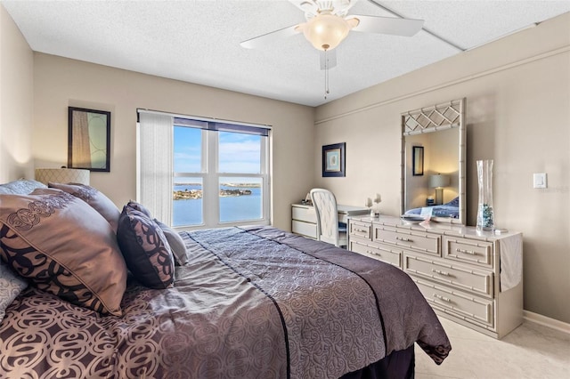 tiled bedroom with ceiling fan, a water view, and a textured ceiling