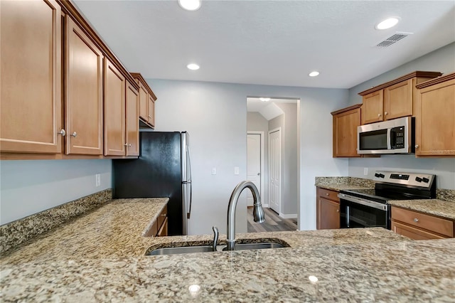 kitchen featuring light stone counters, sink, hardwood / wood-style floors, and appliances with stainless steel finishes