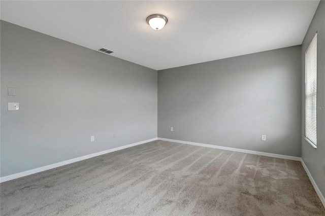 unfurnished room featuring plenty of natural light and carpet