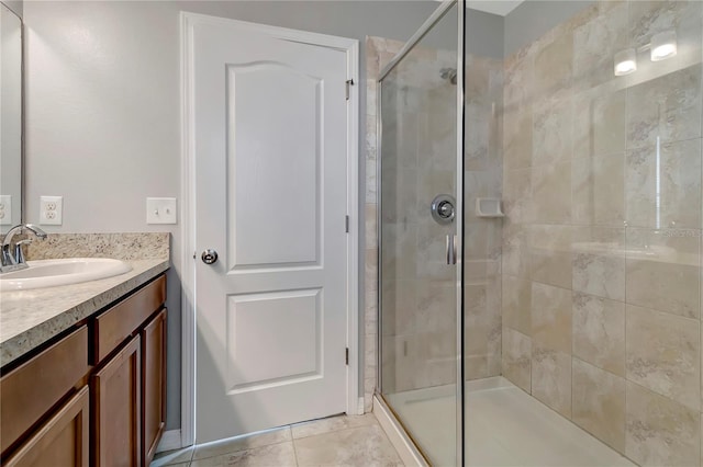 bathroom with a shower with door, vanity, and tile patterned flooring