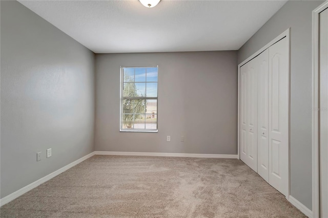 unfurnished bedroom featuring light carpet and a closet