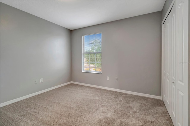 unfurnished bedroom with a closet and light colored carpet