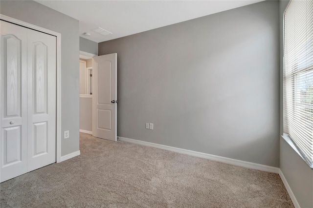 unfurnished bedroom featuring light carpet and a closet