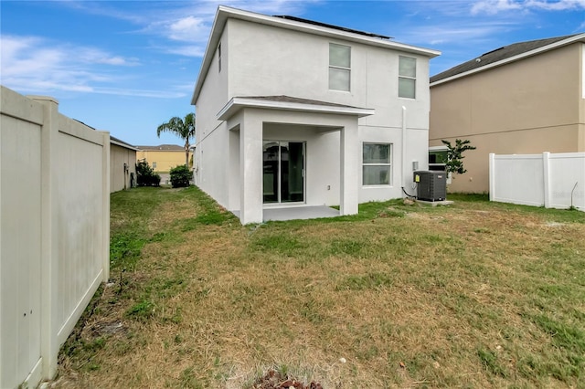 rear view of property with a yard, cooling unit, and a patio