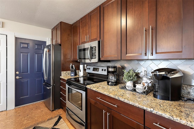 kitchen featuring light stone countertops, decorative backsplash, stainless steel appliances, and a textured ceiling