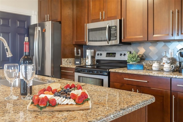 kitchen with decorative backsplash, light stone counters, and stainless steel appliances