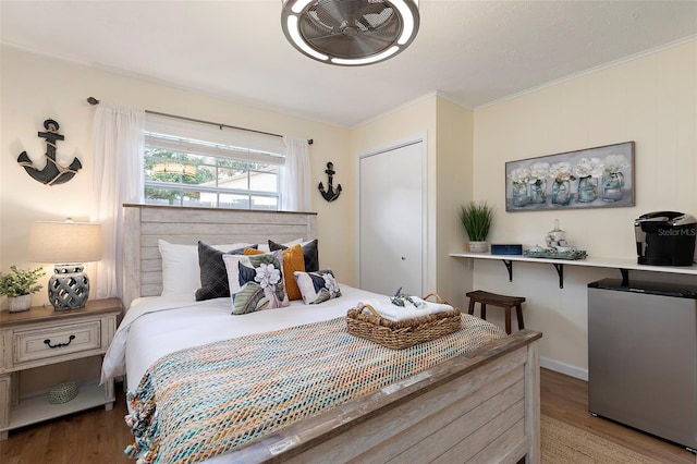 bedroom with hardwood / wood-style floors, a closet, crown molding, and fridge