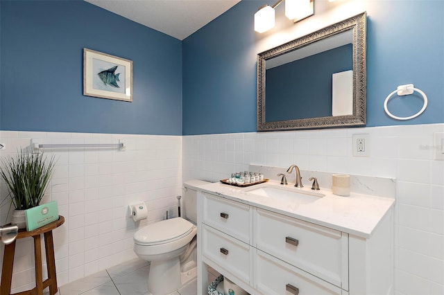 bathroom with tile patterned flooring, vanity, tile walls, and toilet