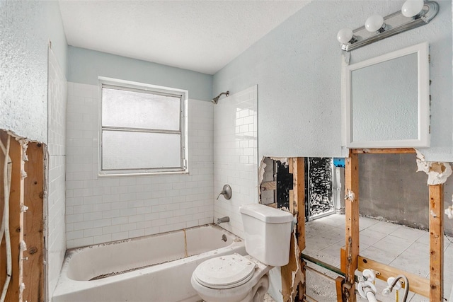 bathroom with tiled shower / bath combo, toilet, and a textured ceiling