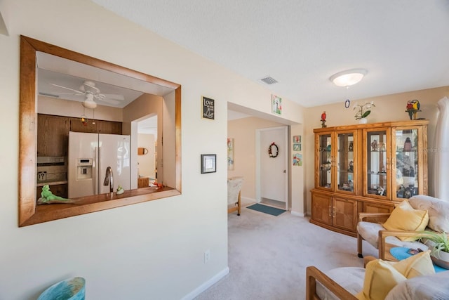 carpeted living room featuring ceiling fan and a textured ceiling