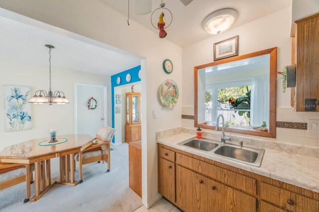 kitchen with sink, hanging light fixtures, and light colored carpet