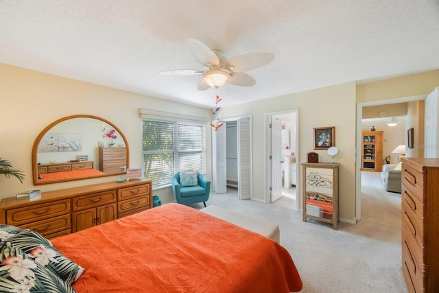 bedroom featuring connected bathroom, a closet, light colored carpet, ceiling fan, and a textured ceiling