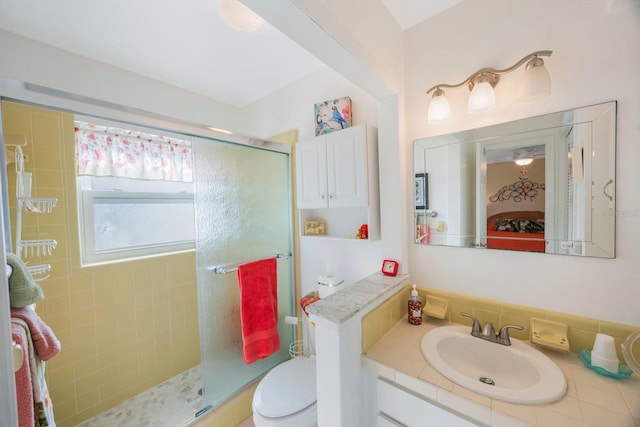 bathroom with toilet, a shower with door, backsplash, and vanity