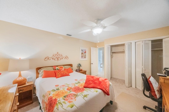 carpeted bedroom featuring ceiling fan and multiple closets