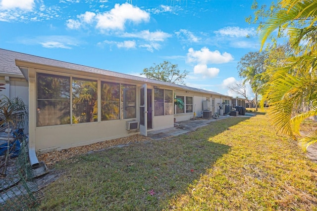 rear view of property featuring cooling unit, a yard, and a sunroom