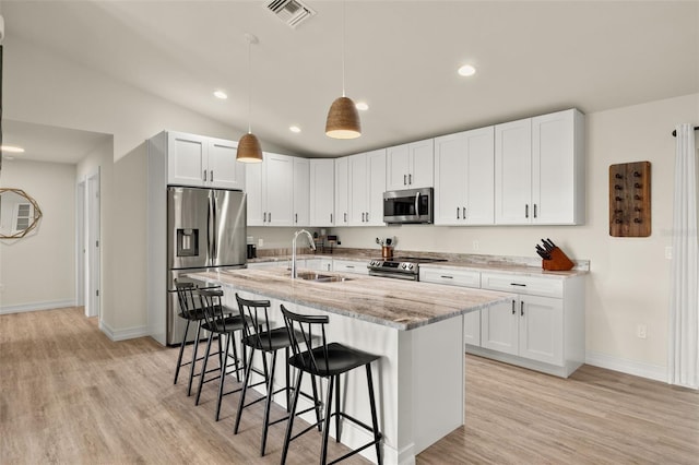 kitchen featuring appliances with stainless steel finishes, light stone counters, white cabinetry, and sink