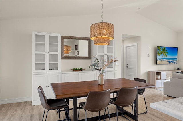 dining room featuring light wood-type flooring and vaulted ceiling