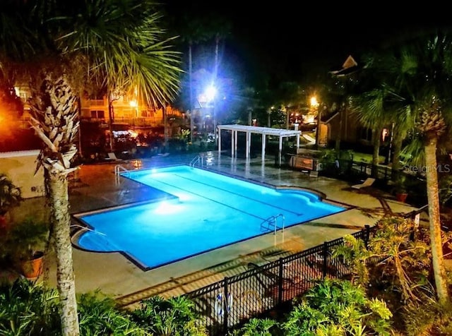 pool at night featuring a patio