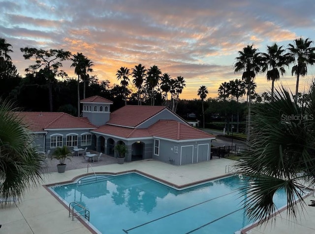 pool at dusk with a patio area