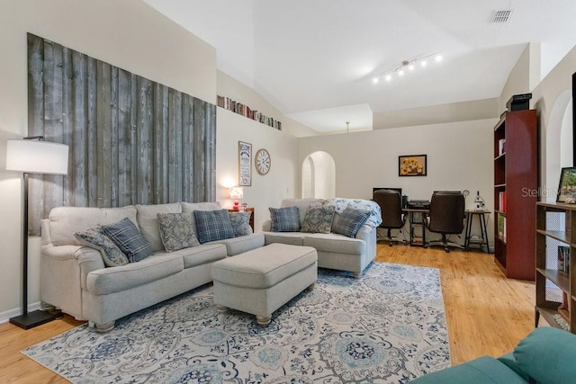 living room with hardwood / wood-style flooring, rail lighting, and lofted ceiling