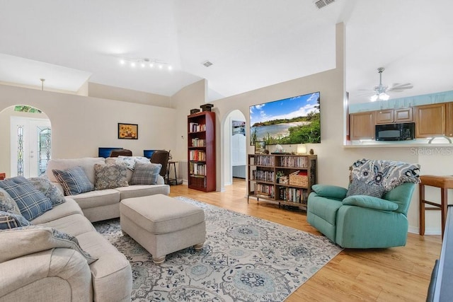 living room with ceiling fan, lofted ceiling, french doors, and light wood-type flooring