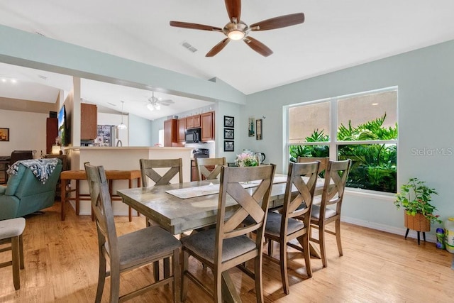 dining space featuring ceiling fan, light wood-type flooring, and vaulted ceiling