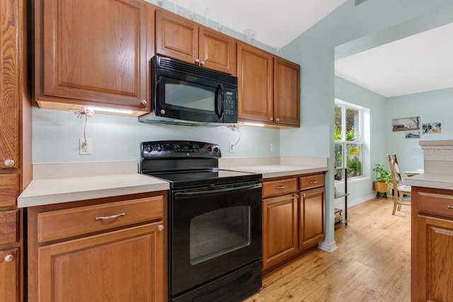 kitchen featuring lofted ceiling, light hardwood / wood-style flooring, and black appliances