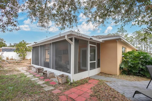 view of side of property featuring a patio area and a sunroom