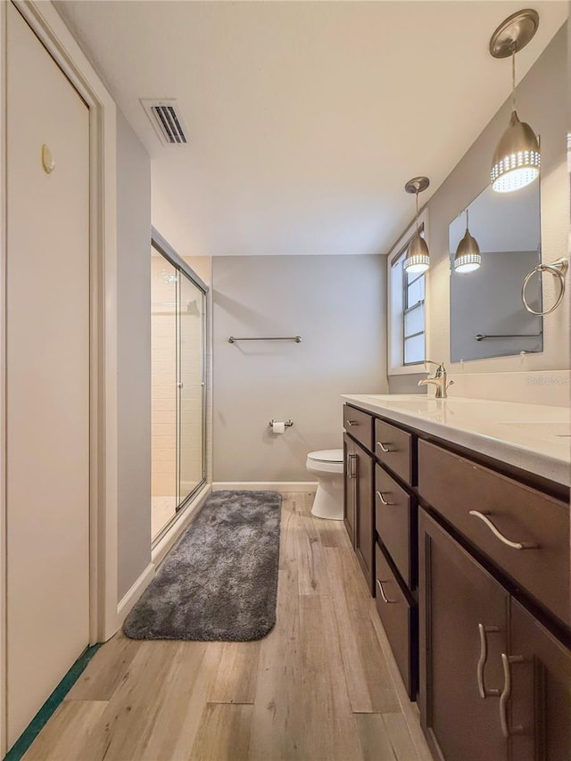 bathroom with hardwood / wood-style floors, vanity, toilet, and walk in shower