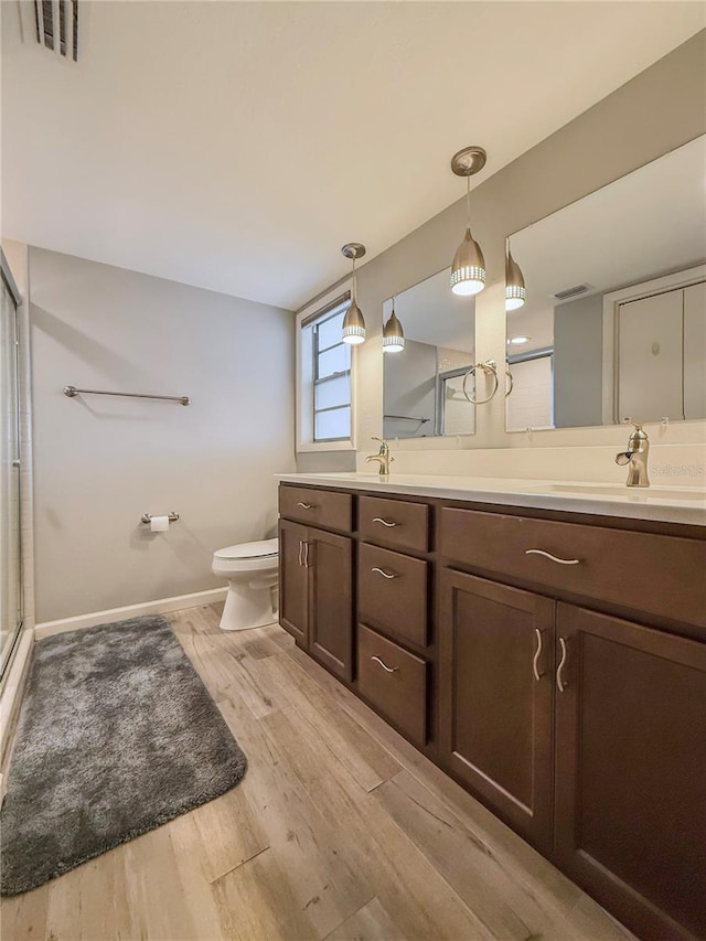 bathroom with wood-type flooring, vanity, toilet, and walk in shower