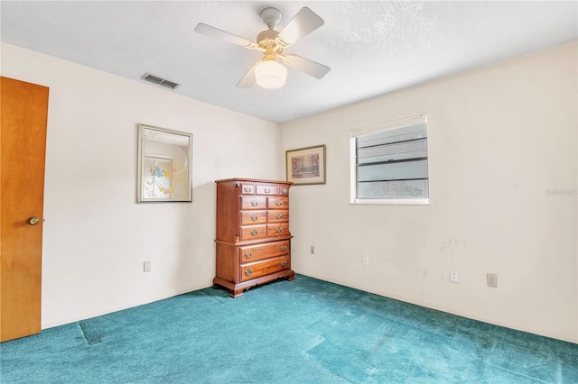 carpeted spare room with a textured ceiling and ceiling fan