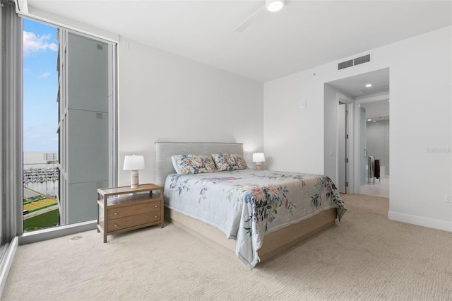 bedroom with carpet floors, expansive windows, multiple windows, and ceiling fan