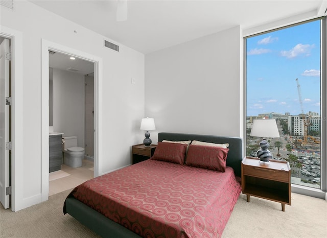 carpeted bedroom featuring floor to ceiling windows, connected bathroom, multiple windows, and ceiling fan