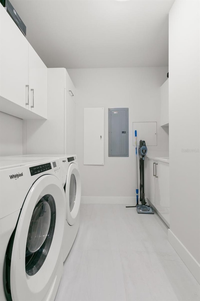 clothes washing area with electric panel, washer and dryer, and cabinets