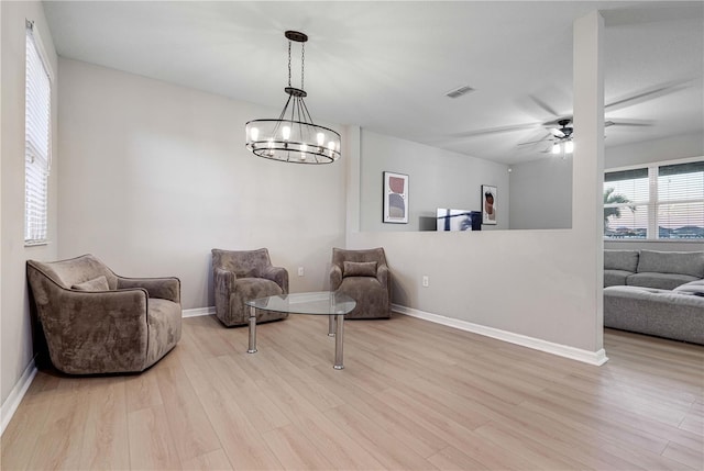 sitting room featuring ceiling fan with notable chandelier and light wood-type flooring