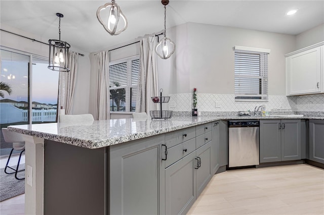 kitchen with tasteful backsplash, stainless steel dishwasher, a wealth of natural light, pendant lighting, and gray cabinets