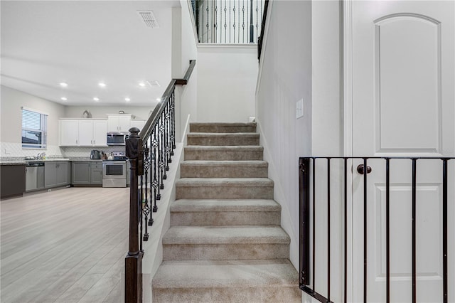 staircase featuring wood-type flooring and sink