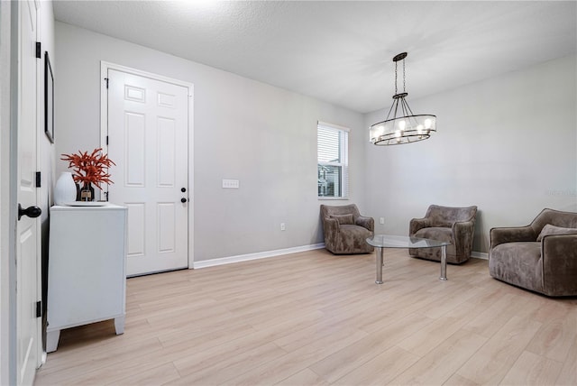 living area featuring a chandelier, a textured ceiling, and light hardwood / wood-style floors