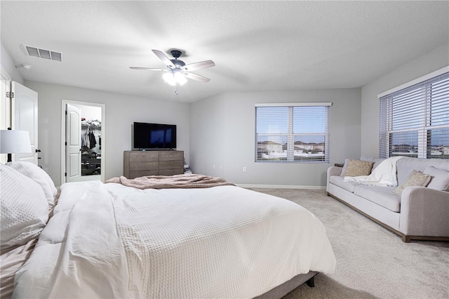 carpeted bedroom with a textured ceiling, a closet, a spacious closet, and ceiling fan