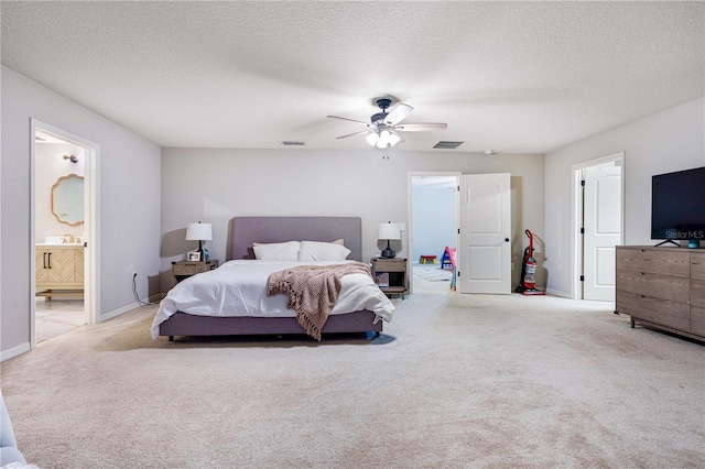 bedroom featuring a textured ceiling, ceiling fan, light carpet, and connected bathroom