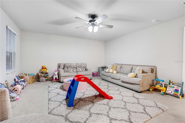 playroom with ceiling fan, carpet floors, and a textured ceiling