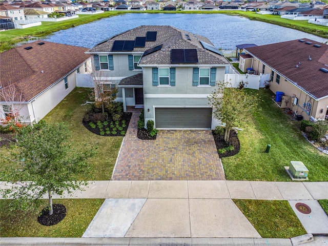 view of front of home featuring solar panels, a water view, a garage, and a front lawn