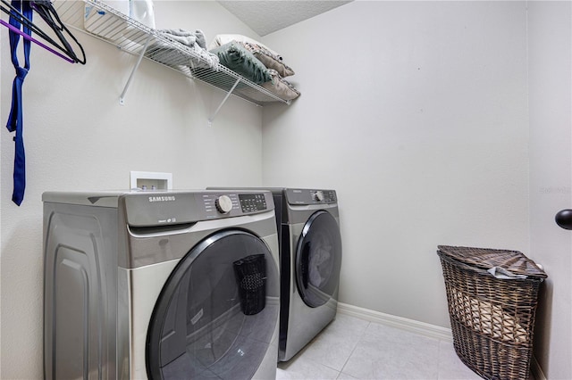 clothes washing area with washer and dryer, light tile patterned floors, and a textured ceiling