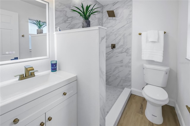 bathroom featuring tiled shower, vanity, toilet, and wood-type flooring