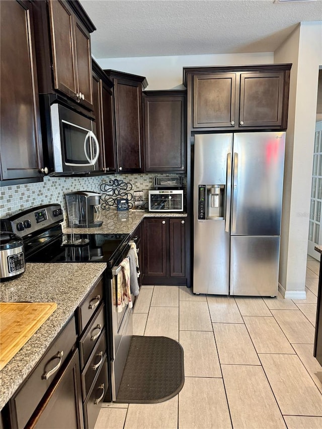 kitchen with stainless steel appliances, tasteful backsplash, light tile patterned floors, and light stone counters