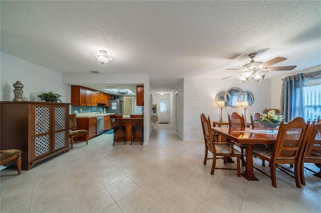 tiled dining room with ceiling fan and a textured ceiling